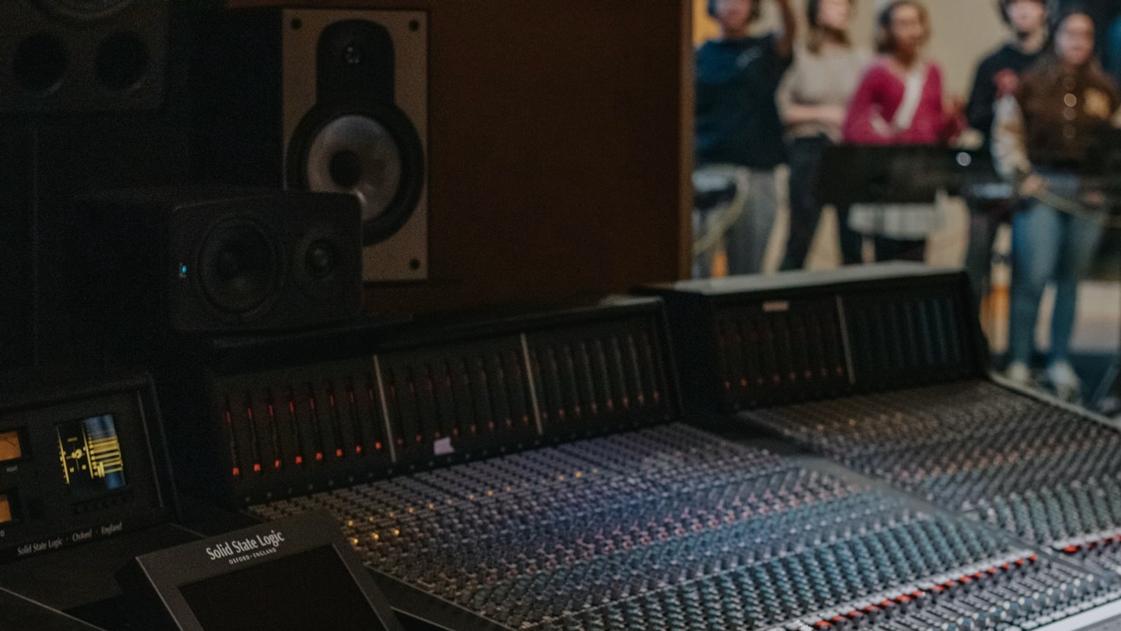 Recording studio mixing console with people in the background