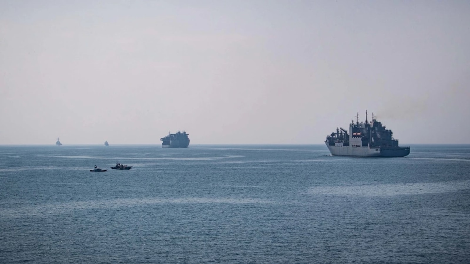 U.S. Navy ships and Iranian small boats transiting the Strait of Hormuz