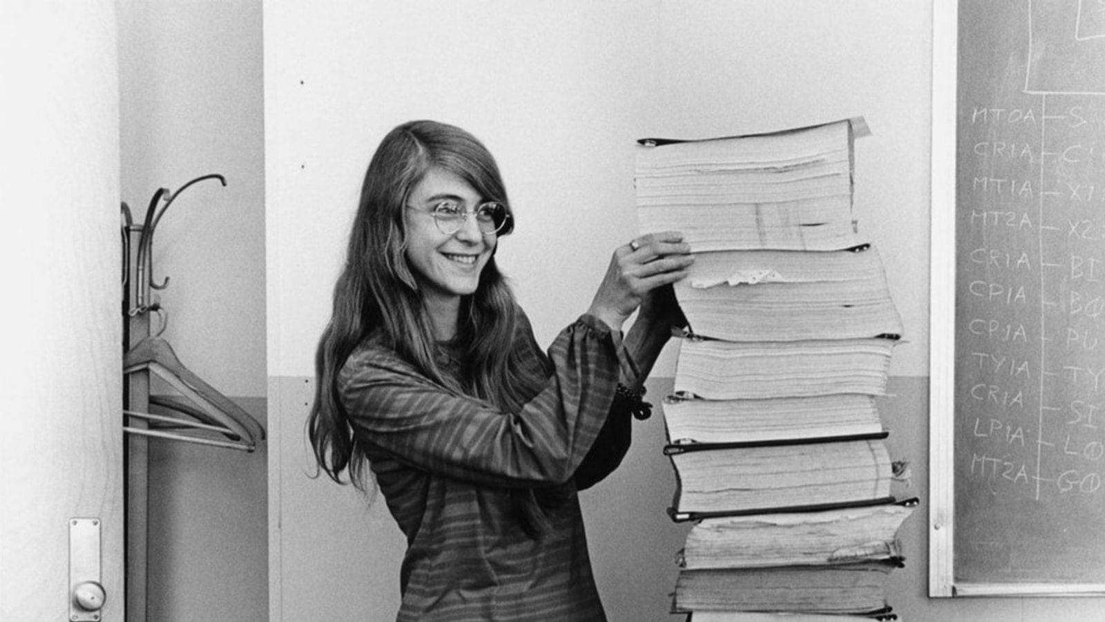 Margaret Hamilton standing beside printed Apollo flight-software listings in 1969