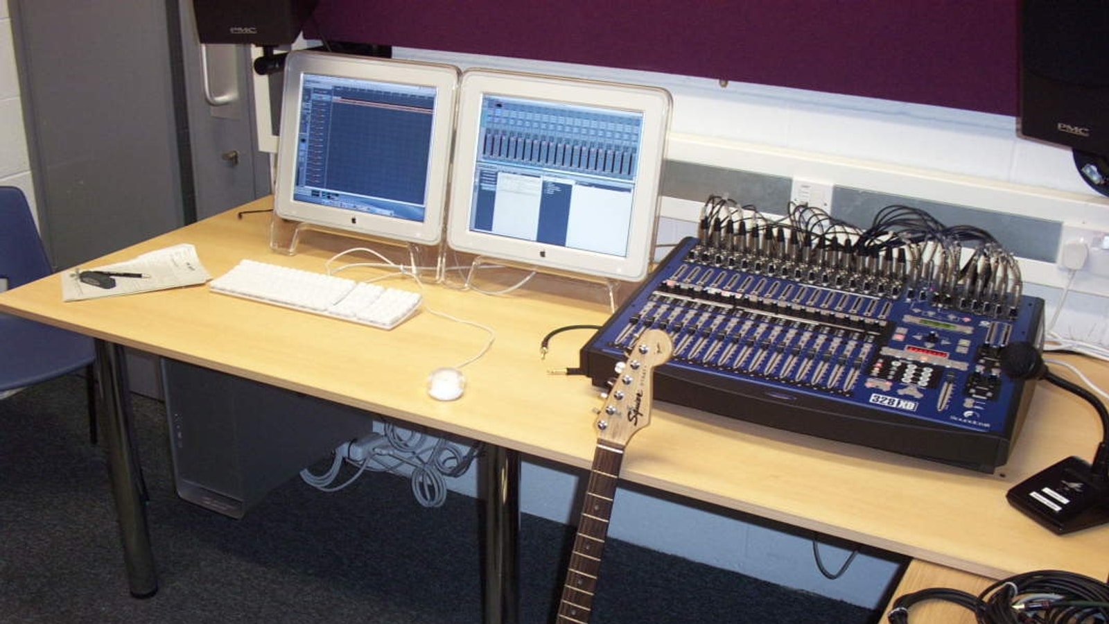 Recording studio control room with mixing console, computers, and electric guitar