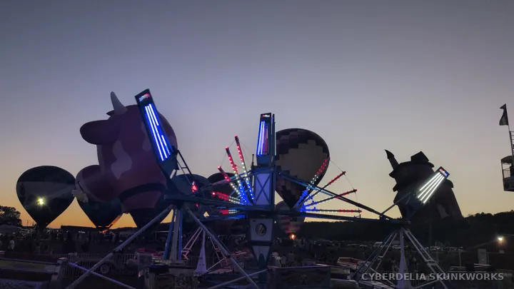 A lit carnival ride turns against the twilight sky.
