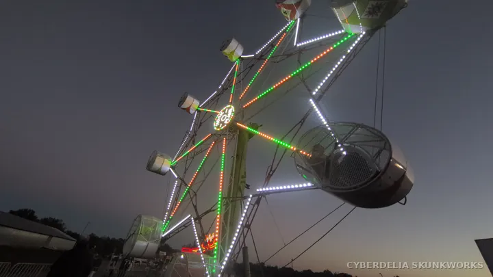 Illuminated ride arms lift passenger cars into the evening sky.