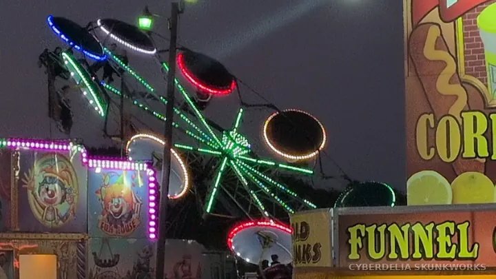 A carnival wheel shines between food stands.