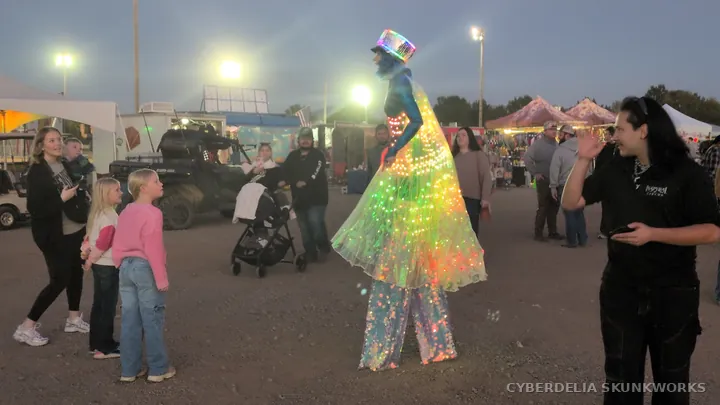 An illuminated Inspyral Circus performer moves through the crowd.