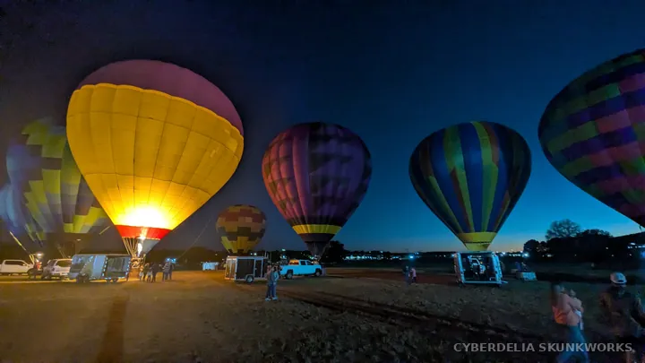 Illuminated balloons and trucks share the fairgrounds after dark.