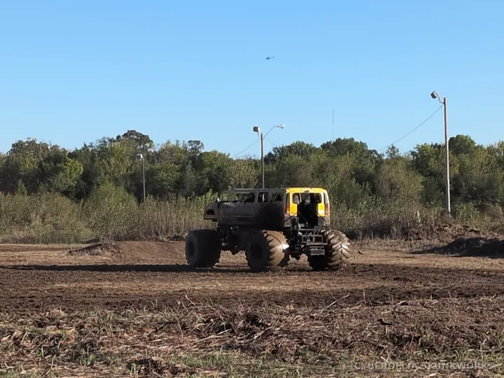 A monster truck crosses the dirt demonstration area.