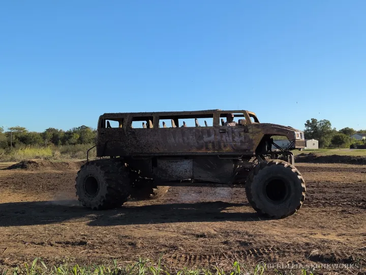 A bus-bodied monster truck stands on oversized tires.