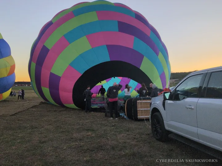 A multicolored envelope opens into a round arch near support vehicles.